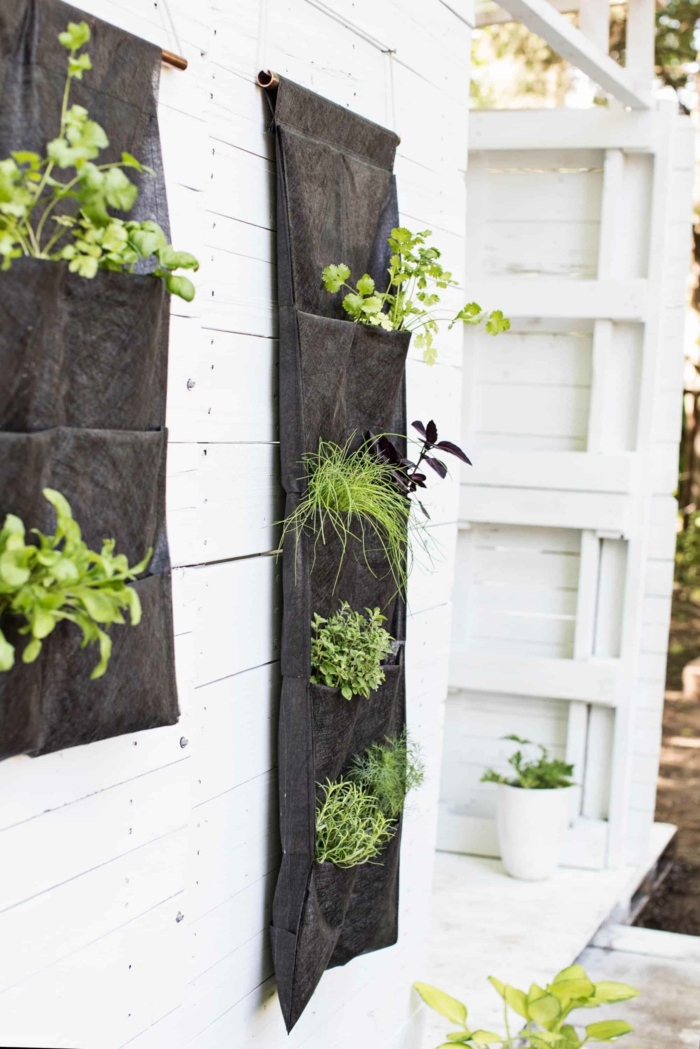 Vertikaler Kräutergarden für einen kleine Raum aus schwarzem Stoff, aufgehängt an weiße Wand, Deko für Garten und Terrasse