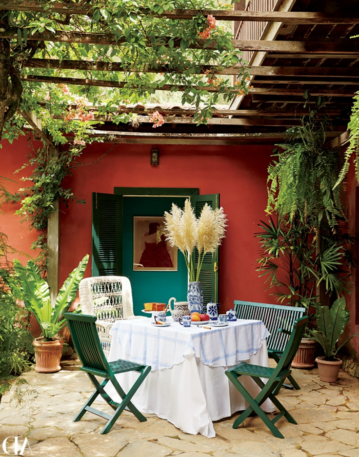 idyllische Gestaltung eines Gartens mit einem kleinen Esstisch und grünen Stühlen, Wände in orange Farbe, pinterest Garten