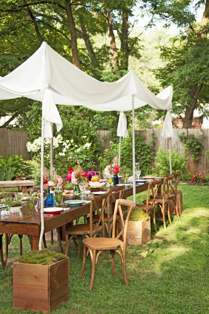 Garten eingerichtet für eine Party mit langem Tisch und weißer Sichtschutz, bunte Blume auf den Tisch, Gartengestaltung Ideen Bilder