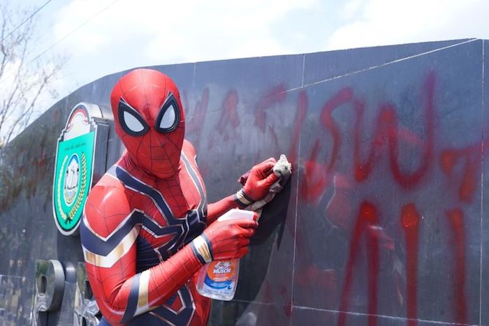 ein mann mit einem kostäum von dem superhelden spiderman, rudi hartono räumt den müll auf