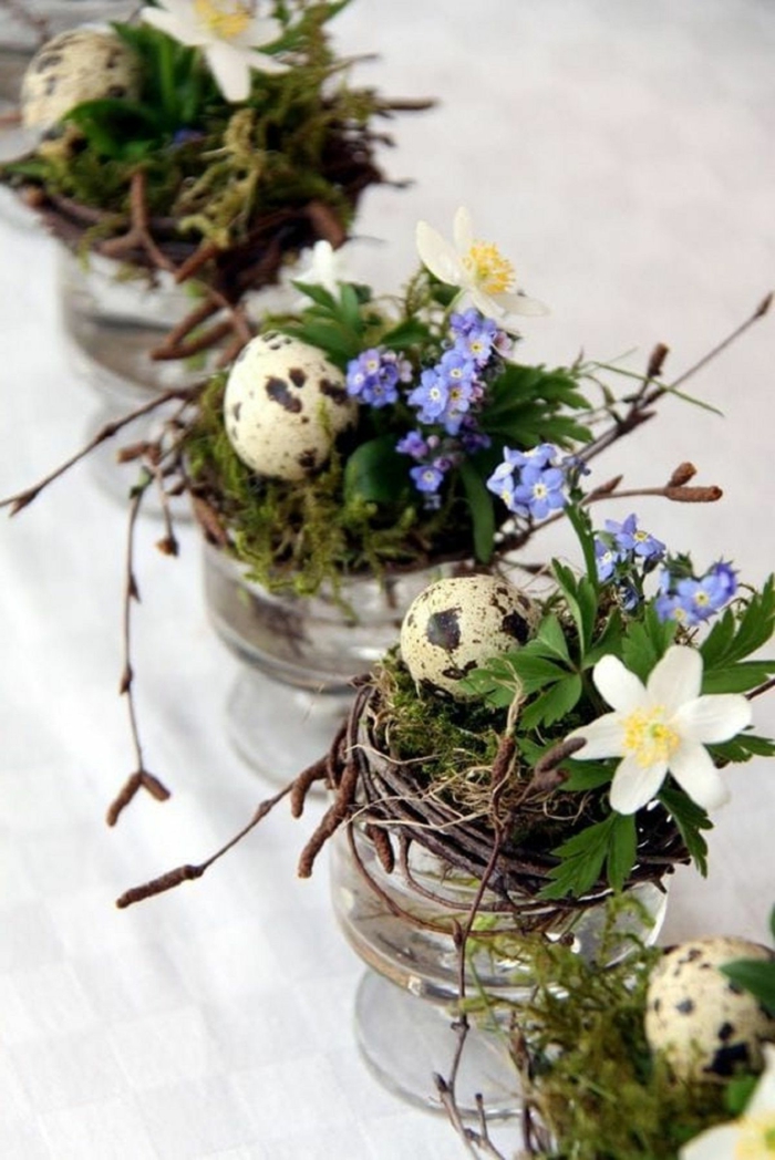 Osterdeko basteln aus Naturmaterialien für den Tisch, kleine Vasen mit kleinen Kränzen mit weißen und blauen Blumen und Eier,