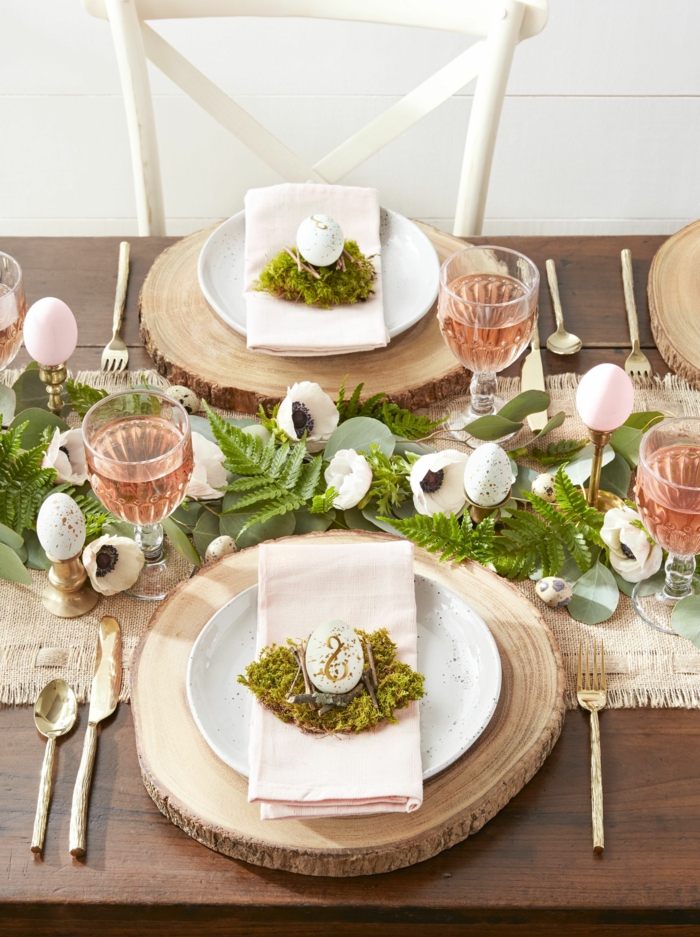 Tischdeko Frühling mit Naturmaterialien, Teller auf einem runden Holzbrett, Tafelaufsatz aus weißen Blumen und grünen Blättern