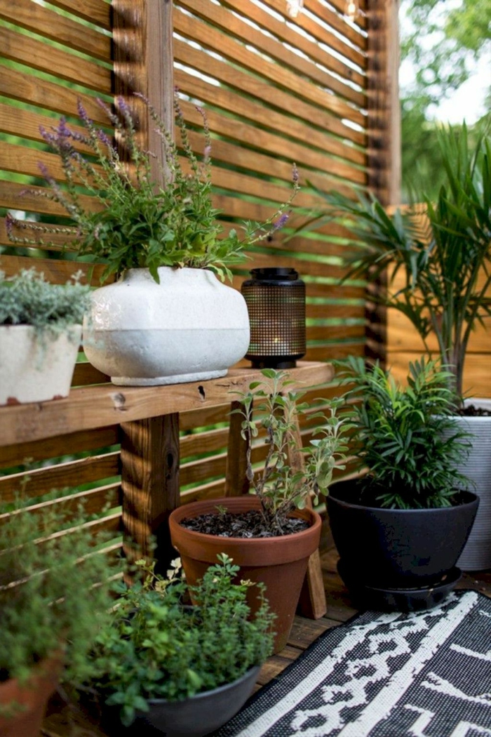 Mit Pflanzen dekorierter Garten, Sichtschutz aus Holz, Garten Ideen selber machen, schwarz weißer Teppich