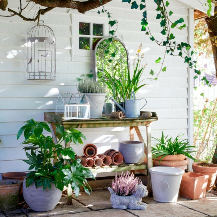 Spiegel in einem Garten, viele Pflanzentöpfe und Gartenzubehör, weiße Wand, Ideen Gartengestaltung modern