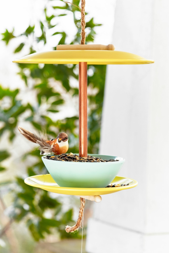 Garten Ideen selber machen, DIY Vogelhaus aus alten Tellern in gelb, kleiner Vogel isst Futter aus einer Schale, 
