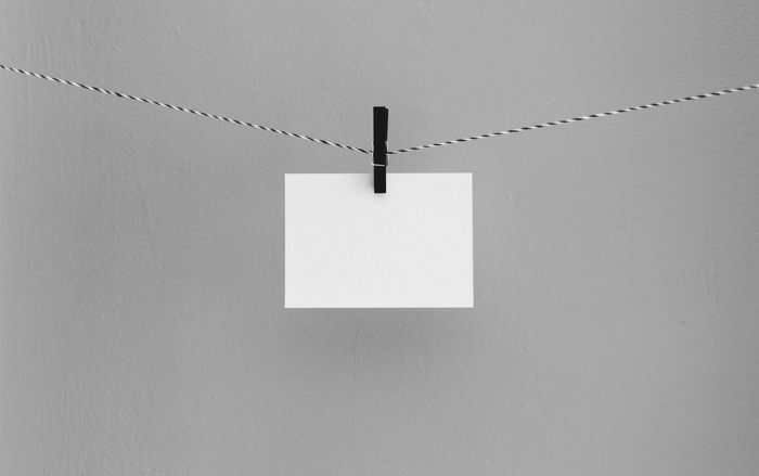 aufgehängter weißer Briefumschlag auf einer Wäscheleine mit einer schwarzen Wäscheklammer, weiße Briefumschläge