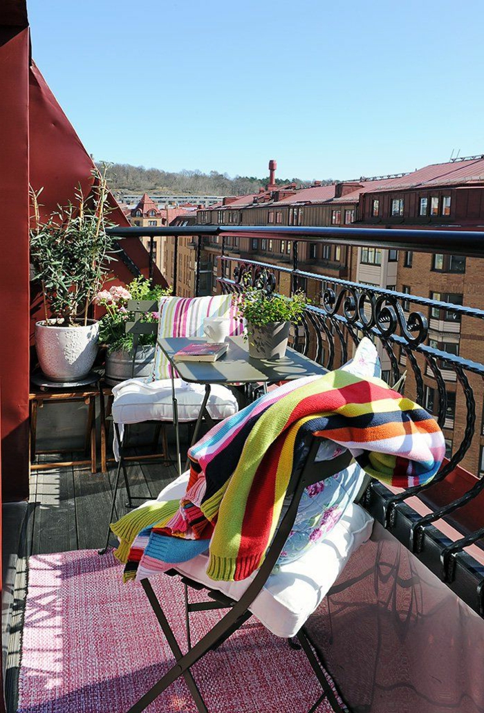 Möbel für kleinen Balkon, bunte Decke auf einem Stuhl, pinker Teppich, rote Wand, Dekoration für Terrasse