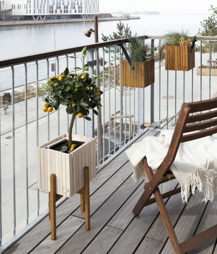 Balkon gestalten Ideen, Stuhl aus Holz mit einer weißen Decke obendrauf, kleiner Zitronenbaum, Aussicht zum Fluss