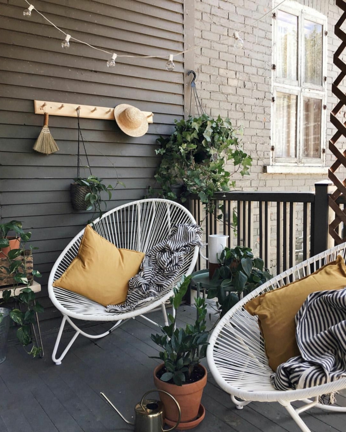 zwei weiße Stühle und gelbe Kissen, Möbel für kleinen Balkon, aufgehängte grüne Pflanze, schwarz weiße Decken
