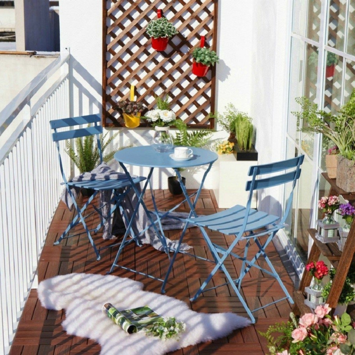 Balkonmöbel Set für kleinen Balkon in blauer Farbe, weißer flauschiger Teppich, Pflanzenständer mit vielen Pflanzen