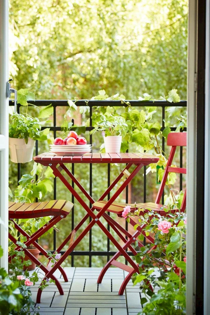 Cozy Gestaltung einer Terrasse, Möbel für kleinen Balkon, zwei Stühle und Tisch in roter Farbe, Äpfel in einem Teller
