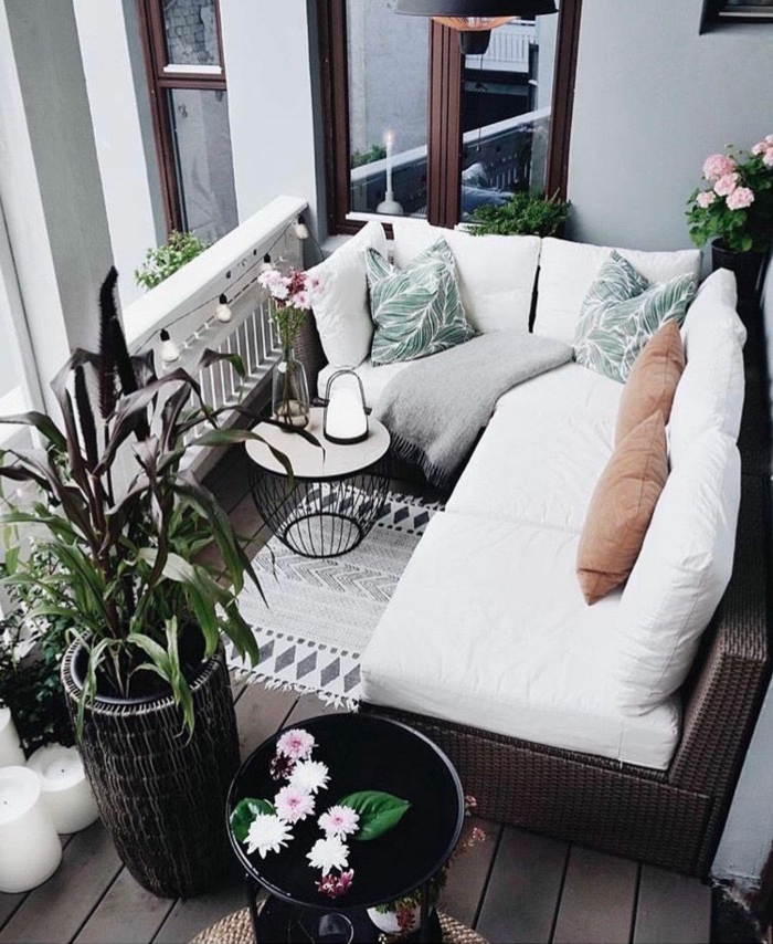 Möbel für kleinen Balkon, Ecksofa mit weißen Kissen, grüne Pflanzen als Dekoration, moderner Korbtisch