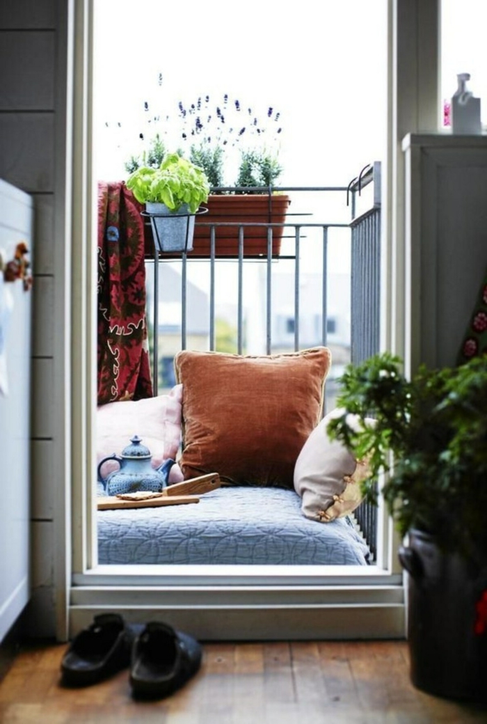 Ikea Balkon gemütlich gestalten mit große Kissen zum liegen, Töpfe mit Pflanzen, Pantoffeln vor der Balkontür, 