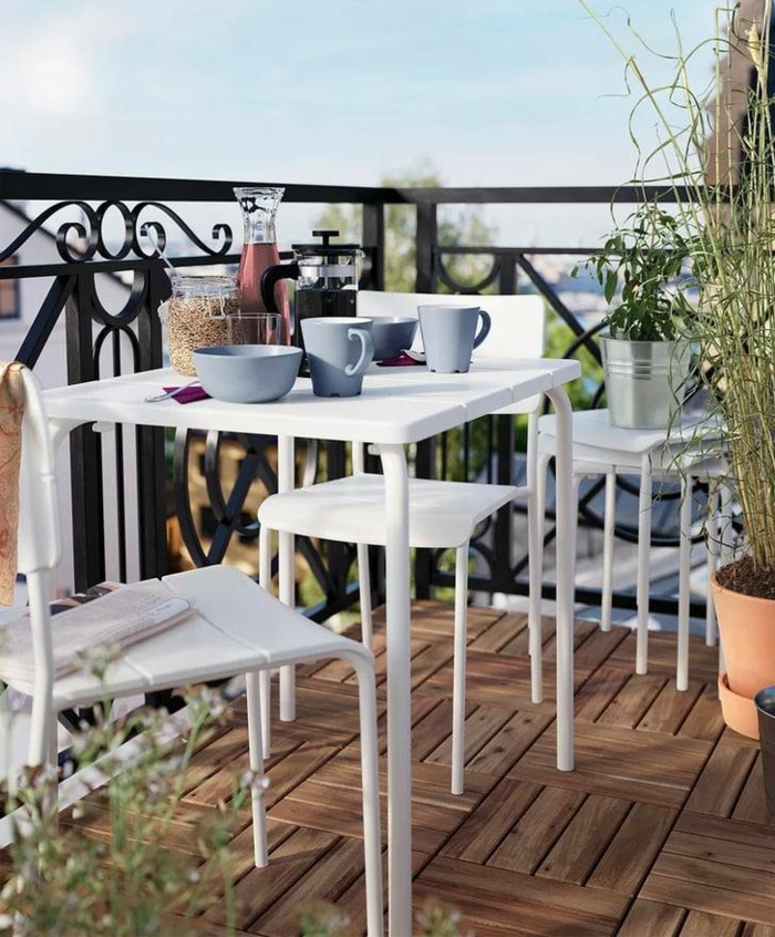 schlichte Einrichtung von Terrasse, weiße Möbel für kleinen Balkon, blaue Tassen und Schalen zum Frühstück
