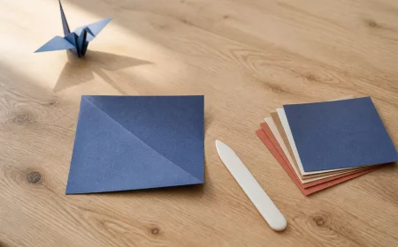 Origami Anleitung: halb gefaltetes blaues Papier auf hellem Holztisch