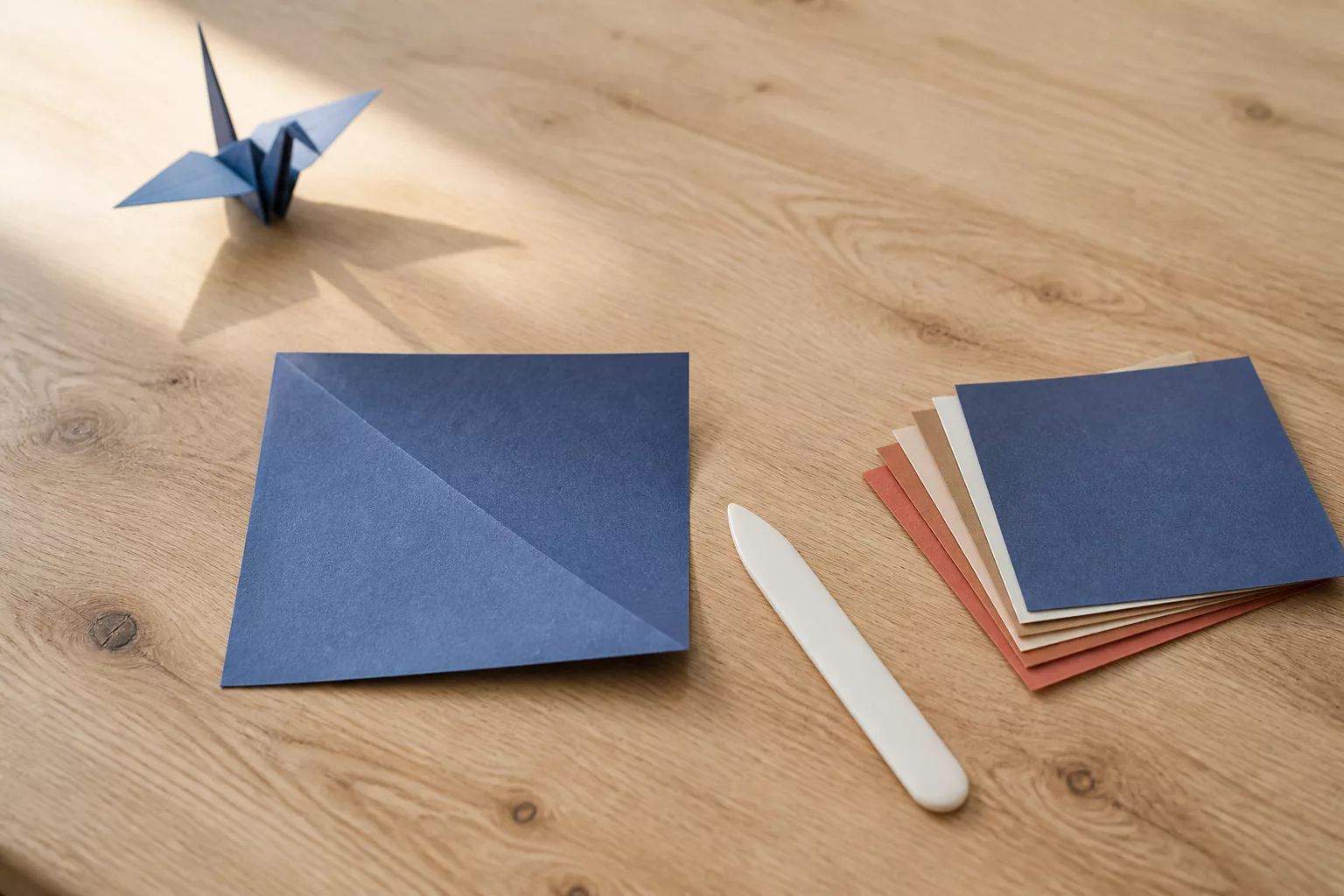 Origami Anleitung: halb gefaltetes blaues Papier auf hellem Holztisch