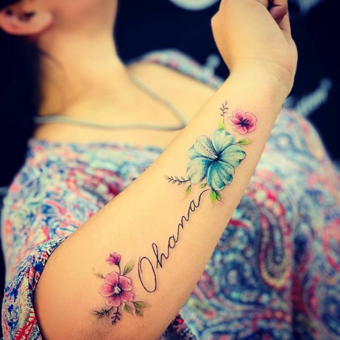 tattoo ideen familie, frau mit wasserfarben tätowierung am unterarm, farbige blüten