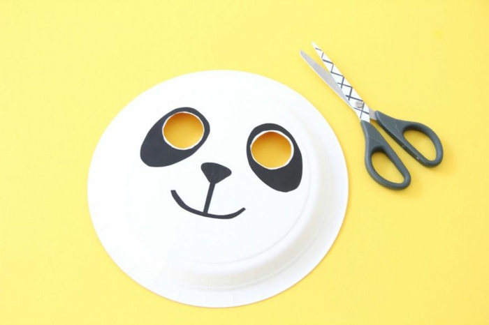 Wie kann man sich Panda Masken basteln, fertige Maske, gelber Hintergrund, schwarze Schere