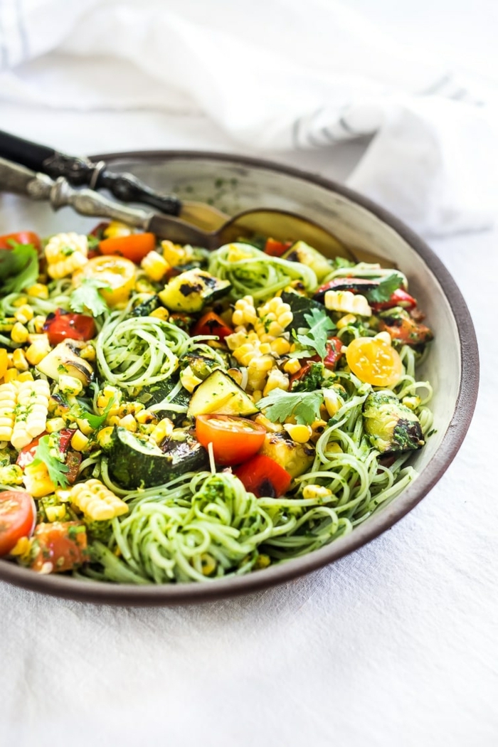 zucchini spaghetti rezept, gesunder salat mit zudeln, chery tomaten, gurken, mais und zitrone
