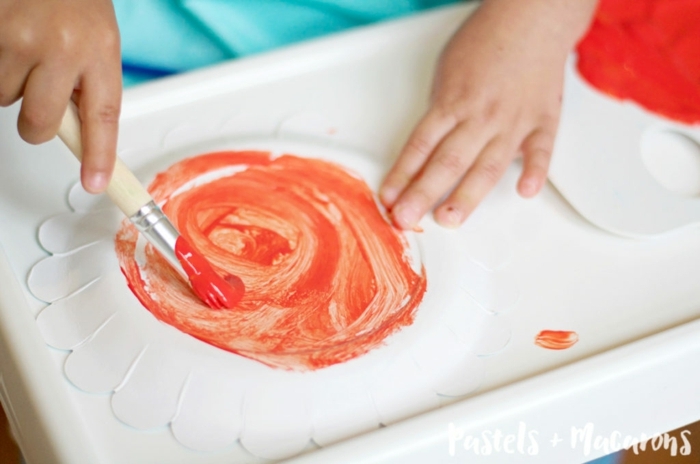 Kind bemalt eines weißen Pappteller mit roter Farbe, Meerestiere basteln, DIY Krabe Anleitung