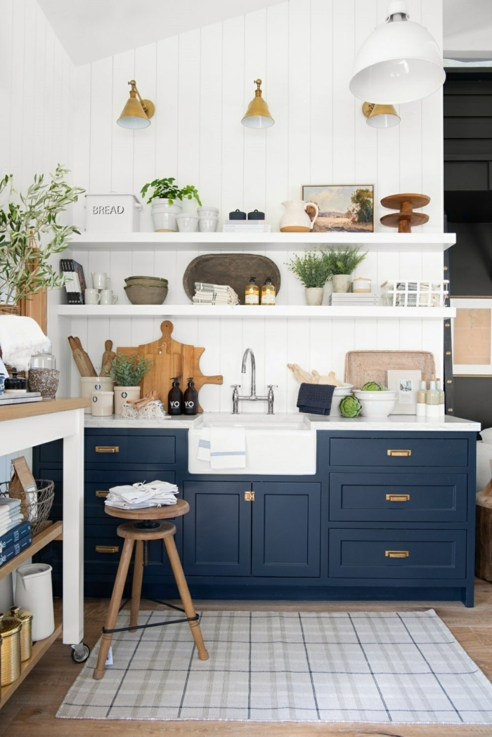 Moderner blauer Küchenschrank, offene Regale mit Küchenutensilien, drei goldenfarbige Lampen, kleine Wohnküche Ideen