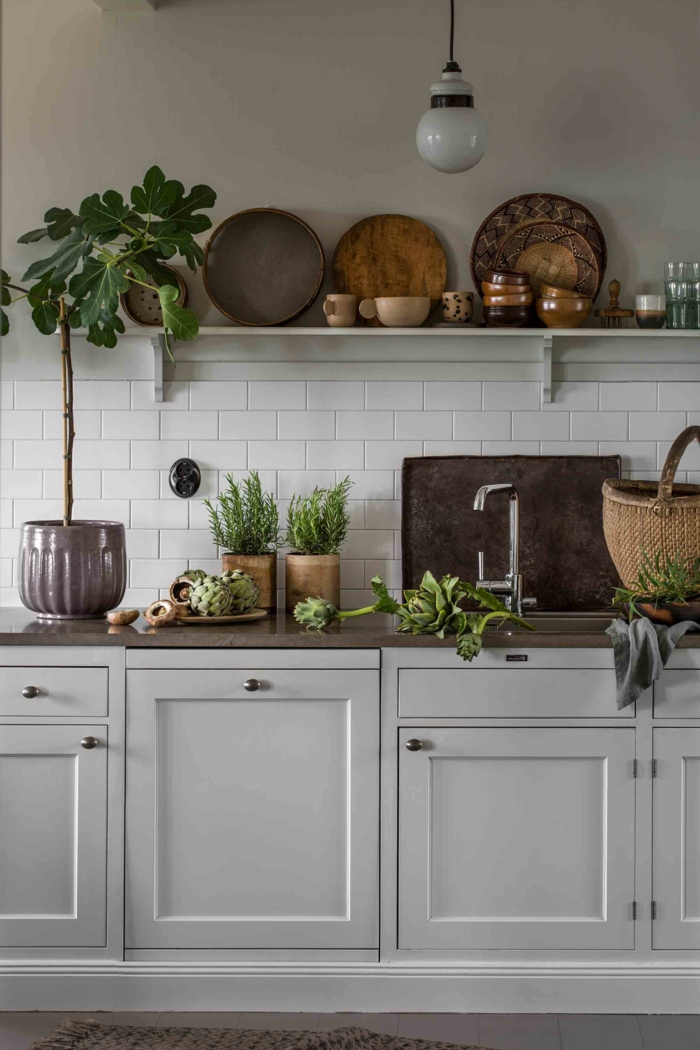 Einrichtung im skandinavischen Stil, Küche modern weiss mit vielen Holztellern, grüne Pflanzen