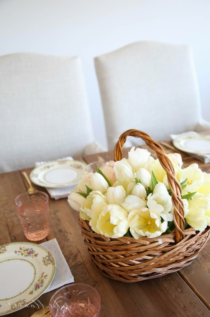 Korb gefüllt mit vielen gelben Tulpen, Tischdeko Frühling mit Naturmaterialien, gedeckter Tisch