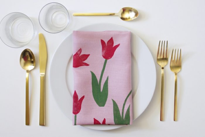 Pinke Serviette mit Abdruck von einer roten Tulpe auf einem weißen Teller, goldener Besteck, pinterest basteln