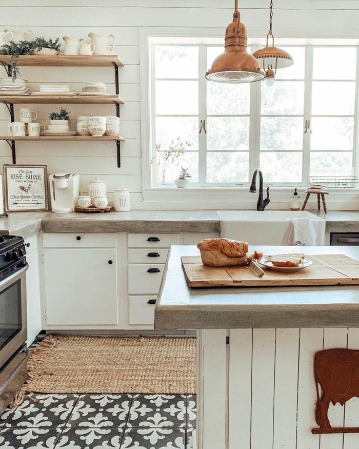 Küche u Form mit Fenster, offene Regale mit vielen Tassen und Tellern, monochrome Einrichtung in weiß, Lampen in Kupferfarbe