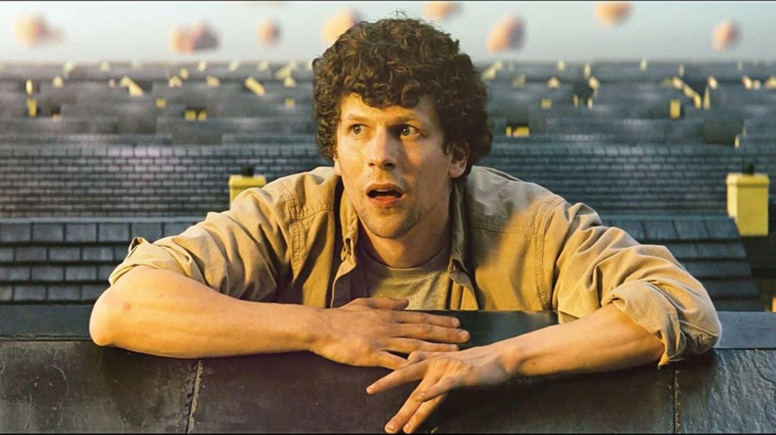 ein mann auf dem dach eines hauses, ein junger mann mit lockigem haar und gelbem hemd, der schauspieler jesse eisenberg in einer szene aus dem film vivarium