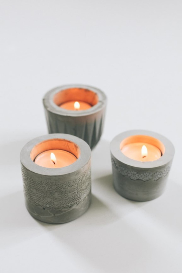 drei kleine Kerzenhalter mit angezündeten Teelichtern, Gefäße aus Beton selber machen, DIY Idee