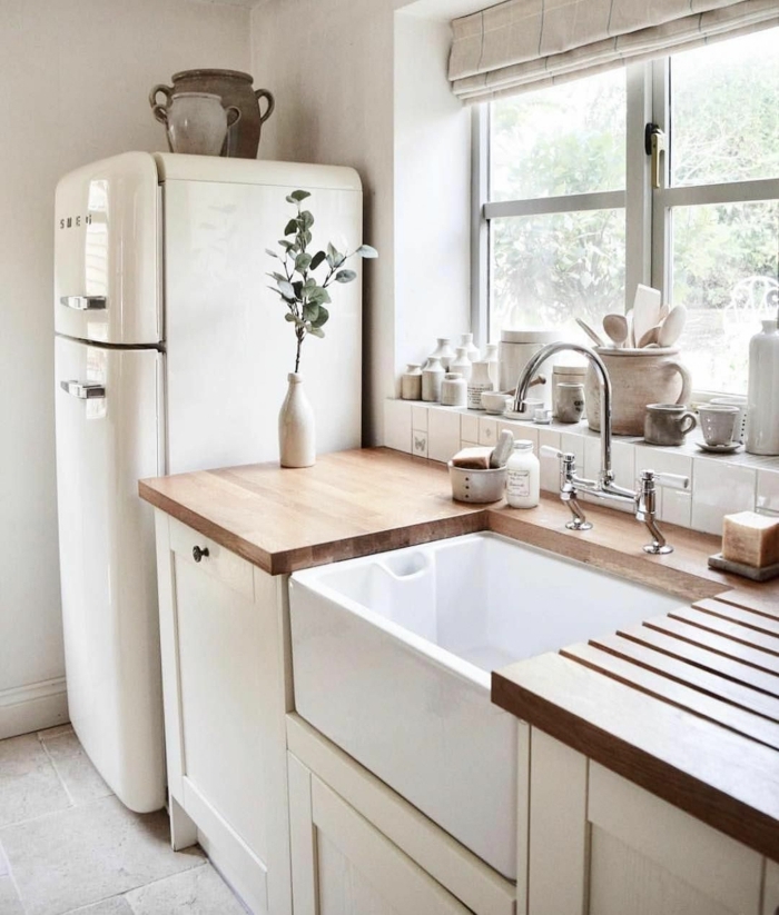 Monochrome Farbgestaltung in weiß mit Arbeitsplatte aus Holz, Küchen Innenausstattung mit Fenster, großer Kühlschrank