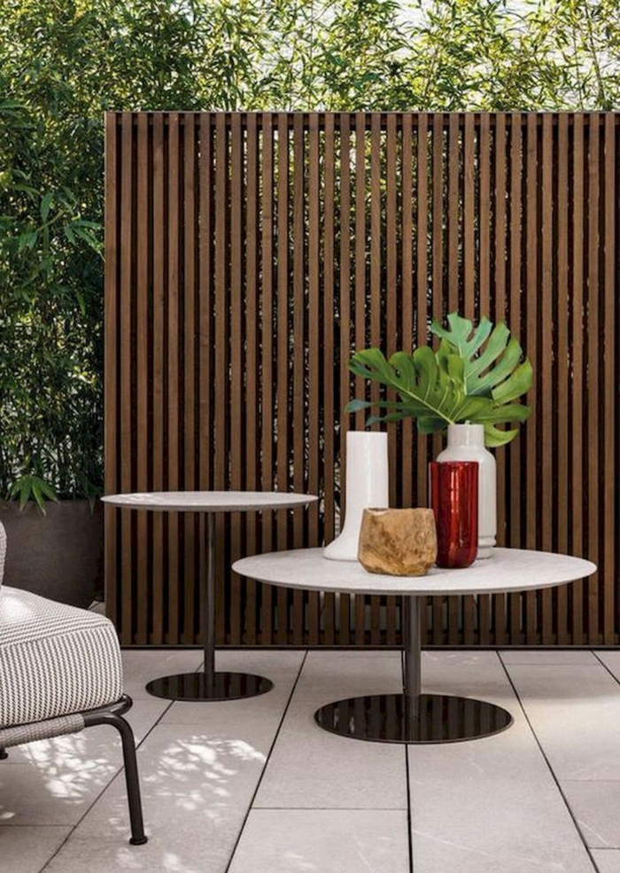 Minimalistische und schlichte Außeneinrichtung, zwei runde Tische, Vase mit grünen Blättern, Zaunideen Sichtschutz Inspiration 