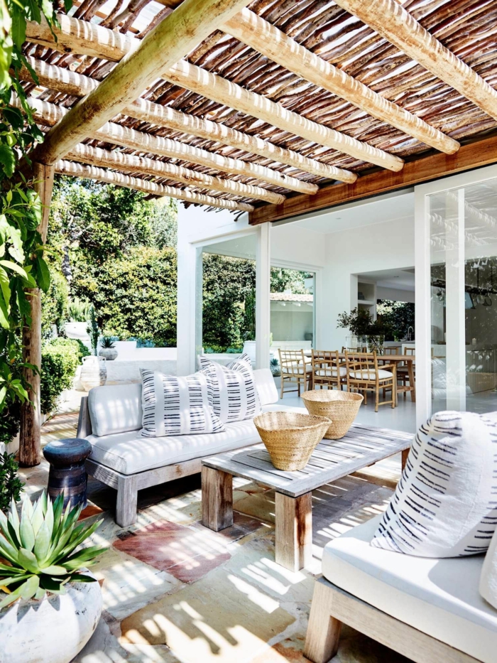 Schutzdach aus runden Holzbalken und Bambus, weiße Gartenmöbel, Sichtschutz Pflanzen Garten 