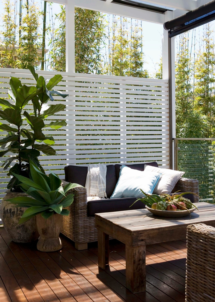 Terrassengestaltung mit Sichtschutz, weiße Lattenrost auf Fenster, Möbel mit schwarzer Polsterung, grüne Pflanzen