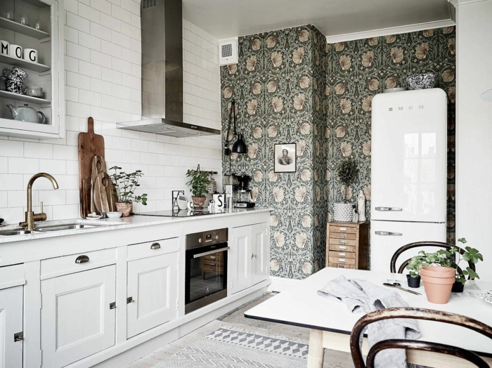Inneneinrichtung im skandinavischen Stil, weiße Schränke und Fliesen, grüne abwaschbare Tapete Küche mit Blumen