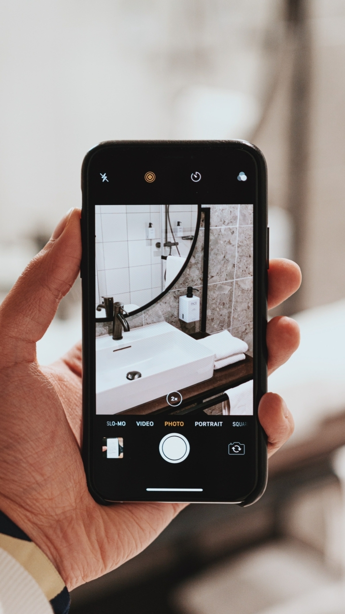 Hand hält ein schwarzes Handy mit einem Foto vom runden Badspiegel, runder Spiegel für Badezimmer Inspiration