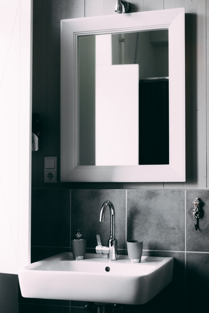 Spiegel mit weißem Rahmen, große graue Fliesen, Badezimmerspiegel beleuchtet, graue Tasse für Zahnbürsten, 