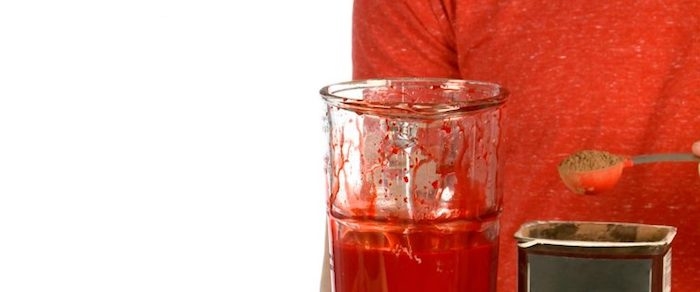 die zutaten für ein diy kunstblut mixer mit einem roten gemisch aus wasser roter lebensmittelfarbe und kakaopulver