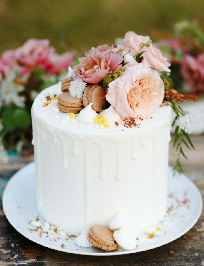 drip cake geburtstag, leckere torte mit weißer schokolade dekroiert mit maccarons und blüten