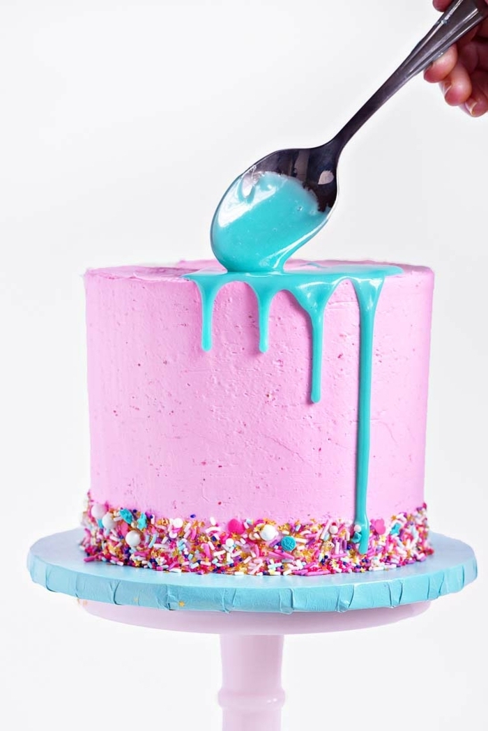 drip cake rezept, schokoladekuchen garniert mit rosa creme, bunte streuseln und blaue ganache