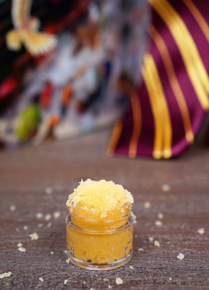 Harry Potter Butterbier Zucker Peeling Rezept, Geschenke aus der Küche, kleines Gefäß gefüllt mit gelbem Peeling, bunte Krawatte im Hintergrund
