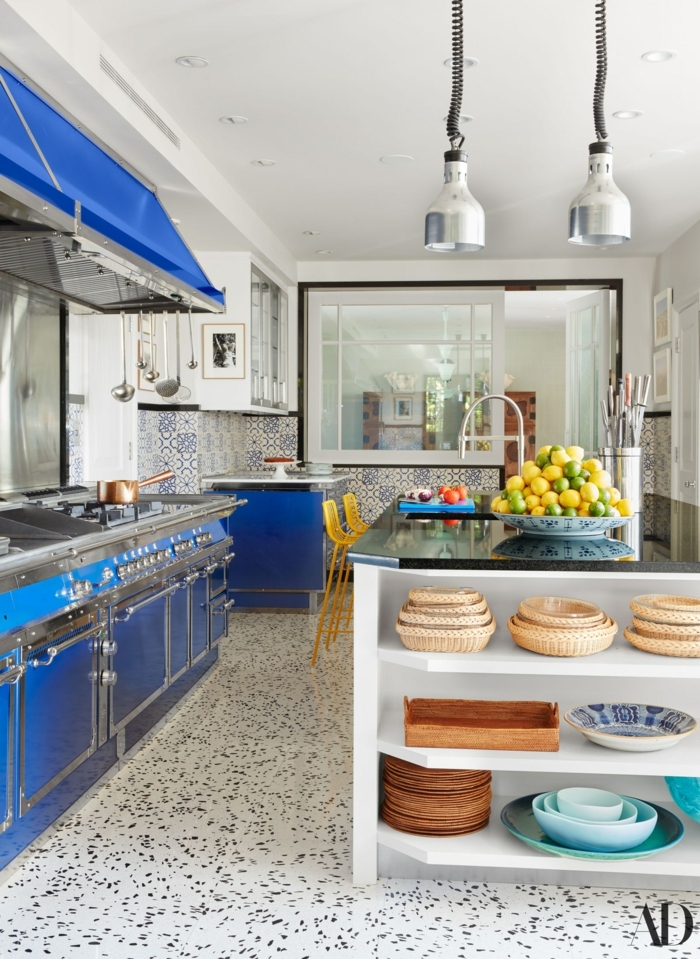 Kochinsel mit Theke, grell blaue Küche und gelbe Stühle, Teller voll mit Zitronen und Limetten, portugiesische Fliesen 