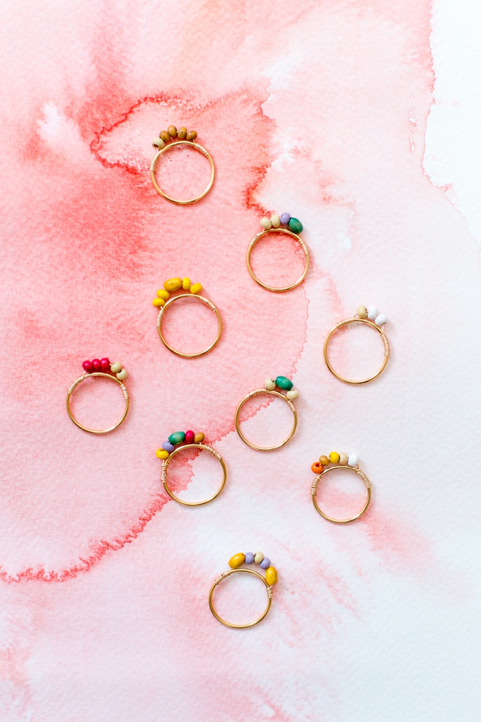 Geschenkideen zum 30 Geburtstag Frau basteln, neun elegante Ringe mit kleinen bunten Steinen dekoriert, Foto mit pinkem Hintergrund