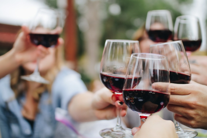 Menschen feiern und stoßen etwas an, sie trinken Rotwein in Kristallgläser, Kristall Weingläser