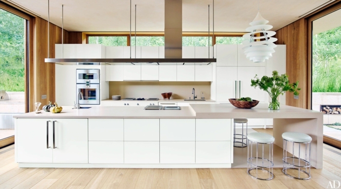 Kochinsel mit integriertem Esstisch, Interior Design von großer Küche in weiße Farbe, Wände in Holztöne, französische Fenster