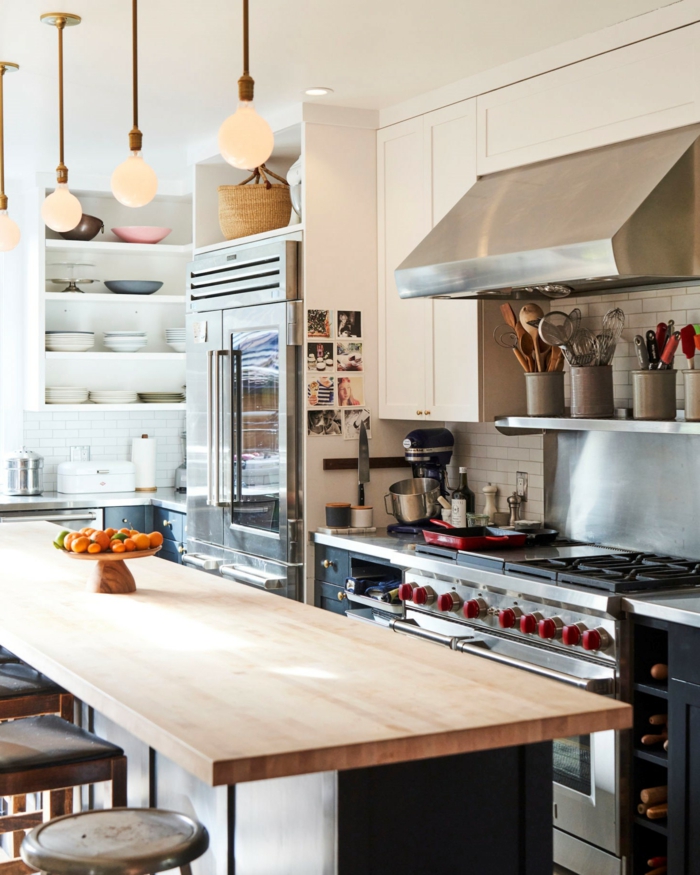 Moderne Küche mit Kochinsel, Theke aus Holz, Metall Ofen, Schränke mit Schüsseln und Tellern, schlichte Lampen