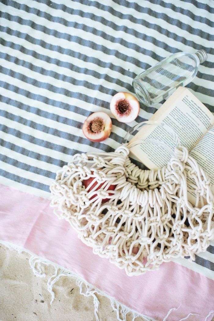 aufgeschlagenes Buch und eine zerschnittene Aprikose, gestreifte schwarz weiß und pinke Decke, Makramee Tasche, selbstgemachte Geschenke für Freundin