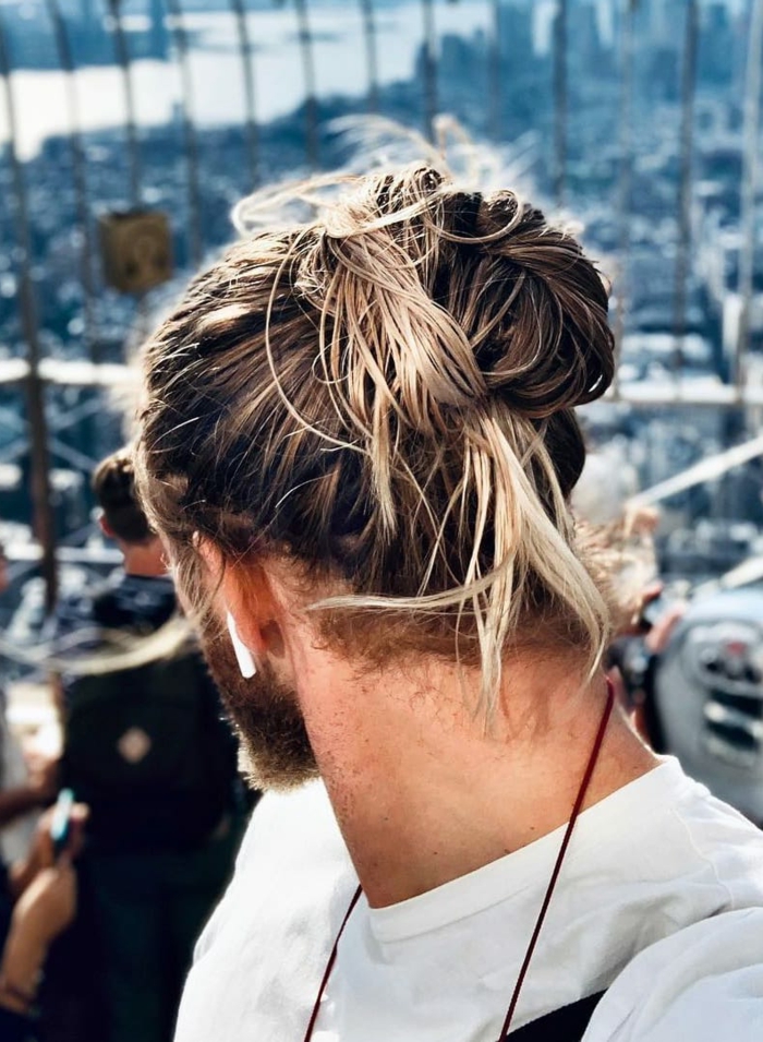 Mann mit hochgesteckten im Dutt langen Haaren mit blonden Strähnen, Frisurentrends 2020 für Männerfrisuren