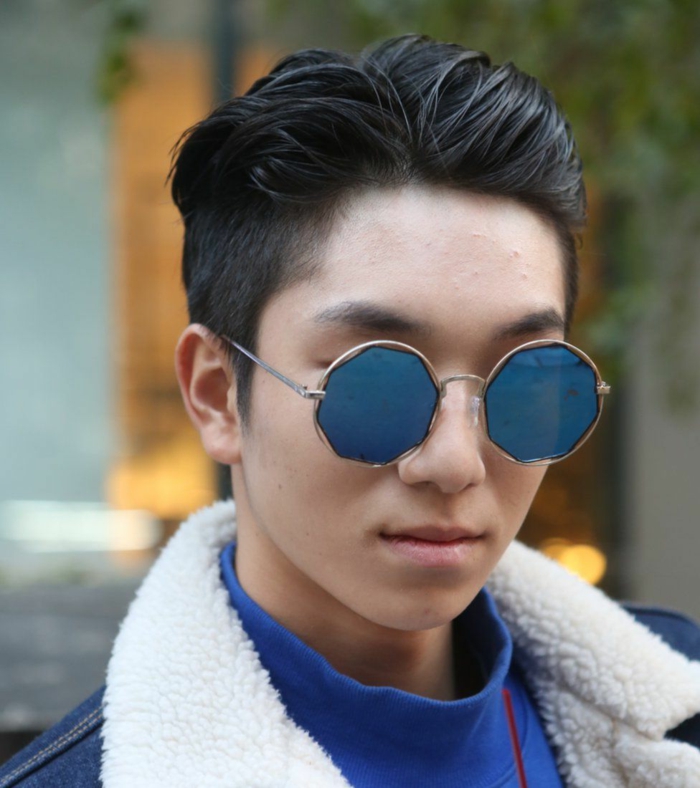 coole runde blaue Sonnenbrillen, junger Mann mit schwarzen Haaren, Trend Frisuren 2020 für Männer, Jeansjacke mit weißem Kragen